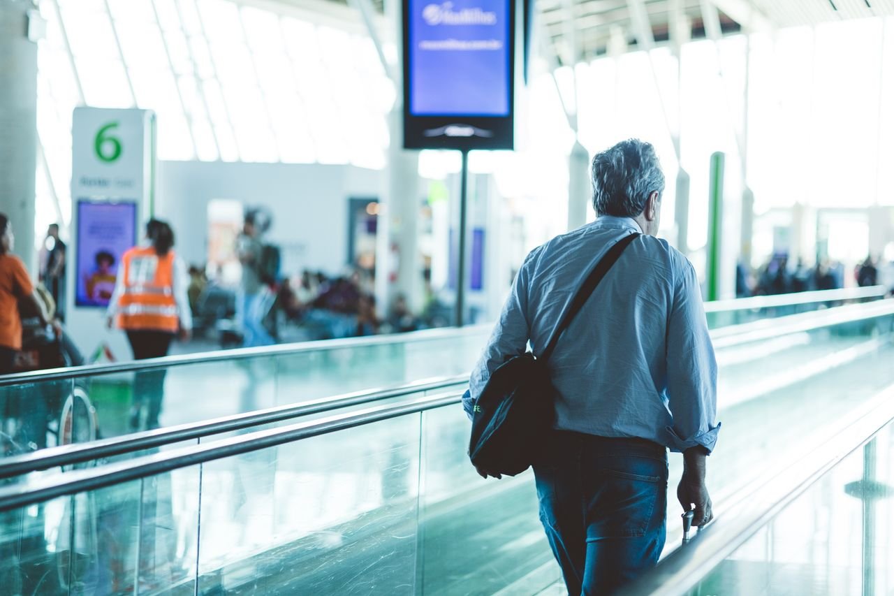 About An adult male walking on an airport travelator, captured in a modern and well-lit terminal.