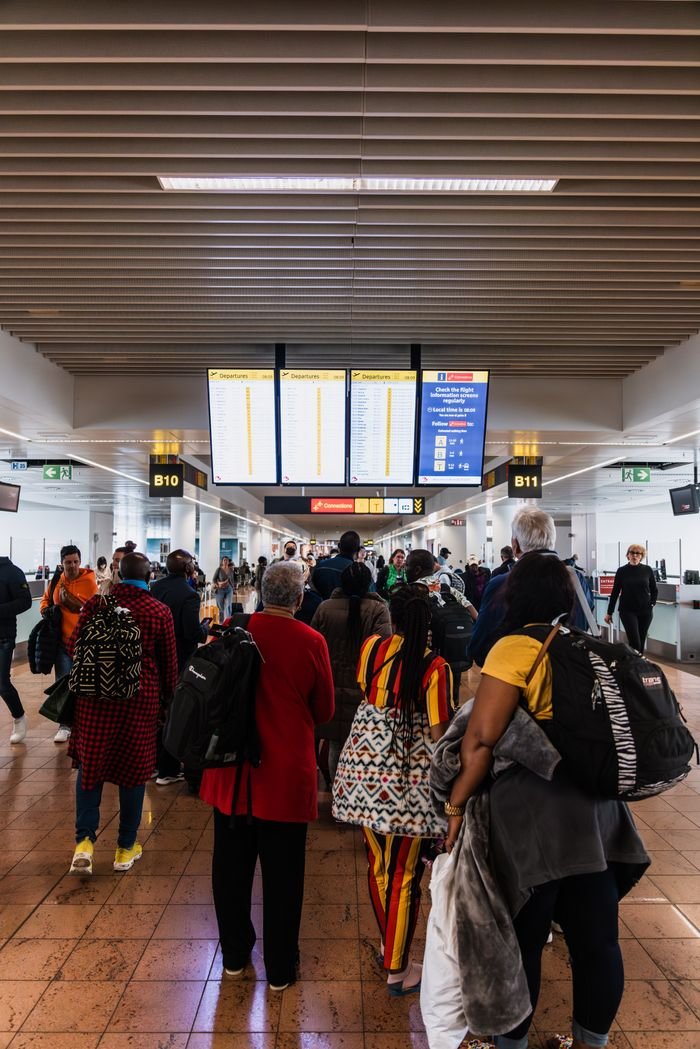 Crafting Captivating Headlines: Your awesome post title goes here Travelers lining up in a busy airport terminal with baggage under flight information screens.