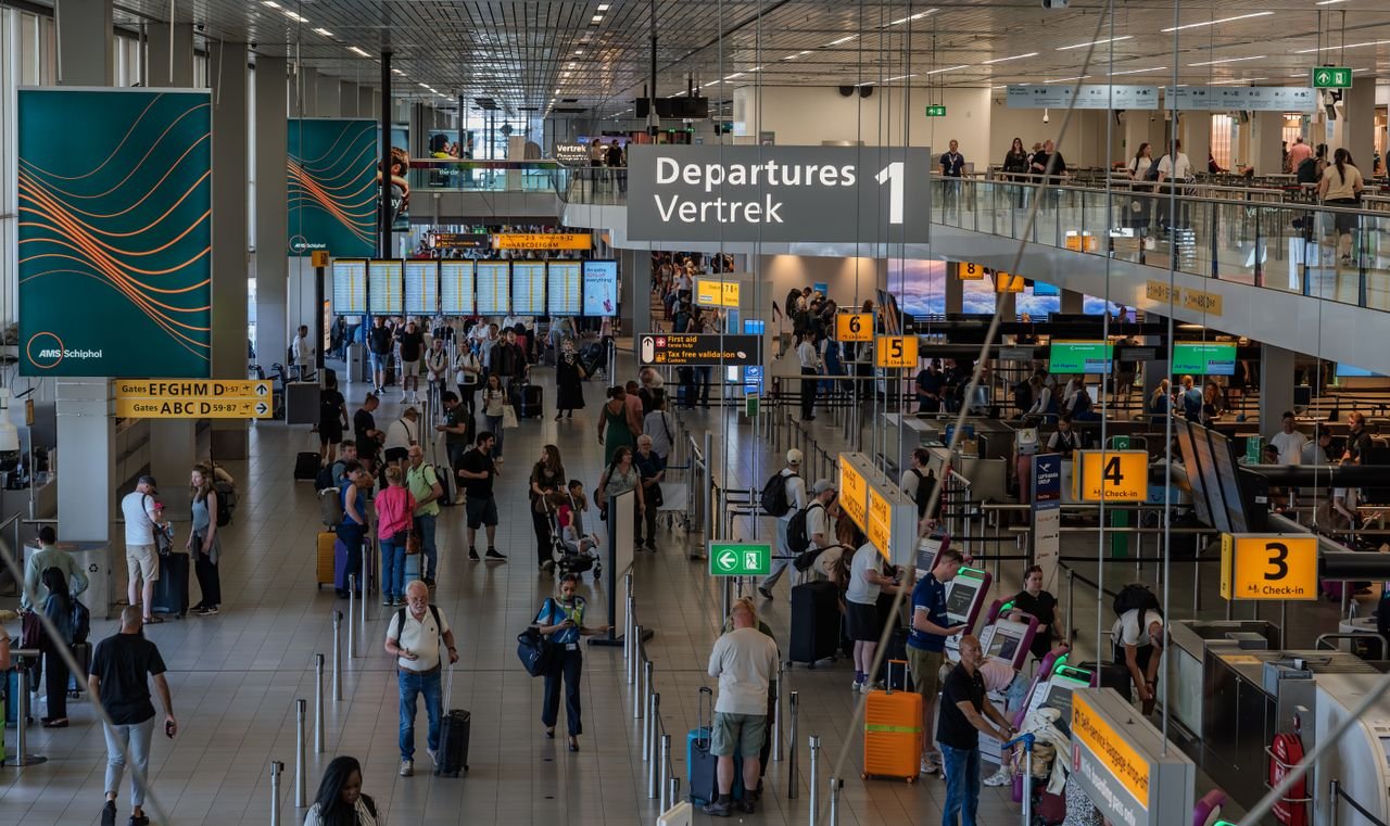 Home Crowds in the departure area of Amsterdam's Schiphol Airport, showcasing bustling travel activity.