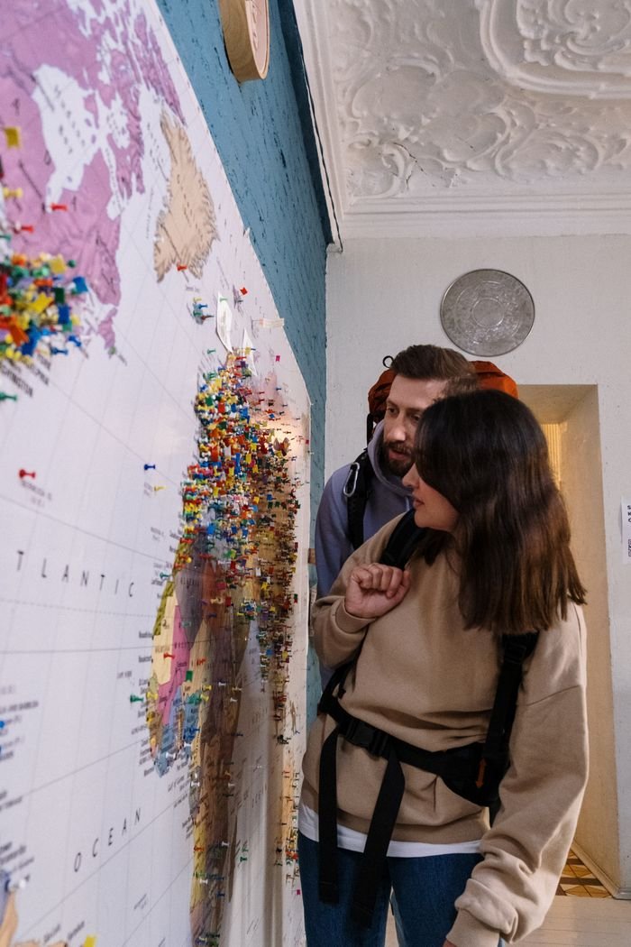 Mastering the First Impression: Your intriguing post title goes here Couple exploring world map with pins, highlighting travel plans in cozy indoor setting.